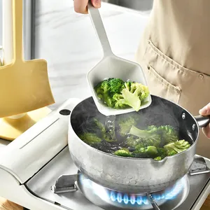 Minimalist white silicone kitchen spatula scoop lifting fresh broccoli from a cooking pot.