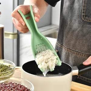 Handgehaltener grüner Silikon Reiswascher zum Abtropfen von Wasser aus weißem Reis in einen Topf