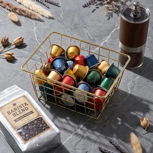 Modern gold wire storage basket for kitchen countertop and coffee capsule organization.