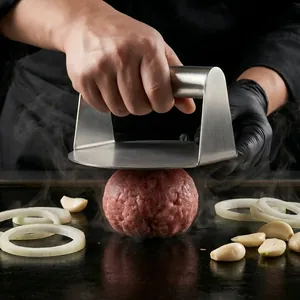 Professional round stainless steel burger press for smashing meat patties on a griddle