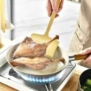 Yellow silicone wide spatula for non-stick pans lifting cooked meat in a kitchen.
