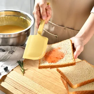 Large heat-resistant yellow silicone spatula used for spreading jam on fresh bread slices