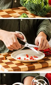 Multi-functional stainless steel kitchen scissors cutting red chili peppers on a wooden board