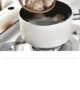 Action detail of brown heat-resistant silicone strainer lifting meatballs from a white pot
