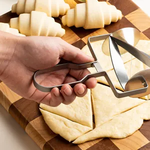 Stainless steel croissant cutter roller slicing dough on wooden board for baking