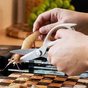 Heavy-duty multi-functional stainless steel kitchen shears cutting raw shrimp on a board