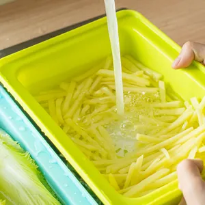 Green PP vegetable washing and draining basket shown with running water in a kitchen