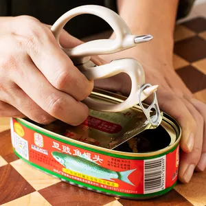 Multi-functional stainless steel kitchen scissors used as a manual can opener on a wooden board