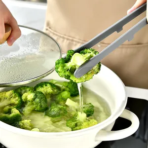 Professional gray food-grade silicone kitchen tongs picking up broccoli from a boiling pot