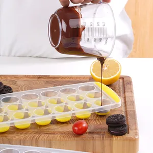 Round ice cube tray with flexible yellow bottom being filled with liquid chocolate