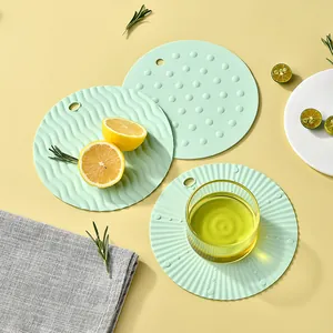 Set of three round light green silicone heat-resistant table mats with unique textures