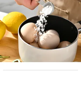 Detail shot of a matte gray measuring spoon pouring coarse salt over eggs in a small white pot
