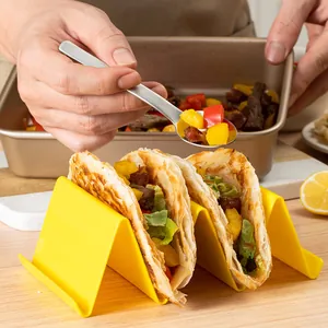 Bright yellow plastic taco holder stand holding delicious loaded tortillas in a kitchen setting