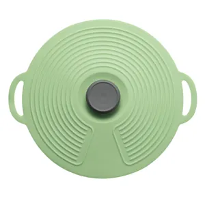 Green silicone spill-proof pot lid with concentric ridges and grey knob handles