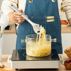Ergonomic silicone pasta server lifting spaghetti from a glass pot in a kitchen setting