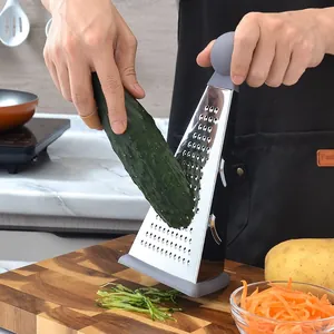 Stainless steel 4-in-1 kitchen grater grating a fresh cucumber on a wooden board