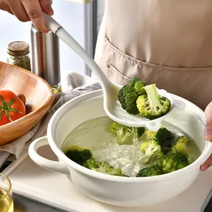 White food-grade silicone colander spoon straining fresh broccoli from a water pot.
