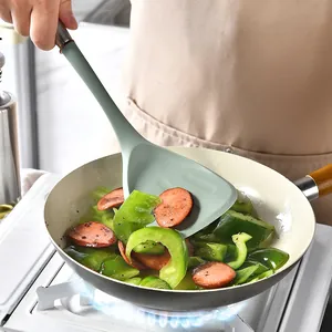 Heat-resistant silicone spatula with stainless steel handle used for stir-frying in a pan.