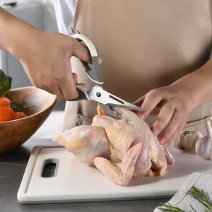 Professional stainless steel kitchen shears for cutting raw chicken bones on a board