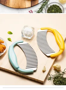 Detailed view of handheld potato wavy cutters in mint and yellow on a wooden board.