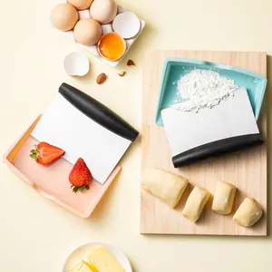 Stainless steel dough scraper set with black handles on a wooden cutting board