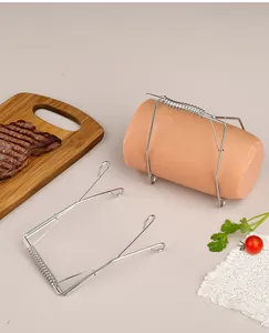 Stainless steel spring meat roll frying clip holding a large sausage on a kitchen table