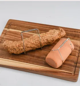 Close-up of stainless steel spring tongs holding meat on a wooden cutting board