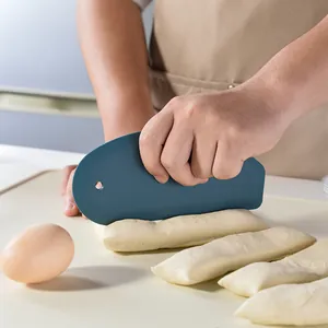 Blue silicone dough scraper with measurements scale used for cutting fresh dough on a mat