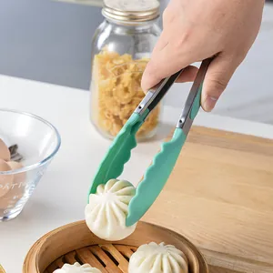 Pinze da cucina in acciaio inox con manici verde menta che raccolgono un panino
