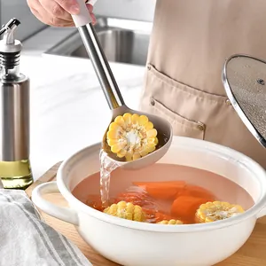 Détail d'une louche en silicone avec manche en acier inoxydable puisant du maïs d'une marmite