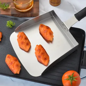 Stainless steel food paddle for pizza and snacks on black grill pan background