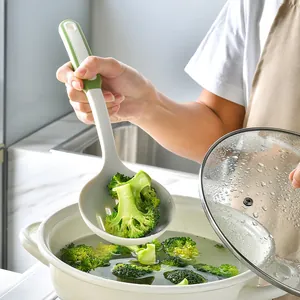 Food grade heat-resistant silicone slotted spoon lifting broccoli from a white soup pot