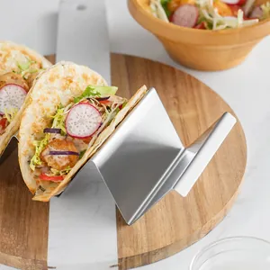 Modern W-shaped stainless steel taco holder displaying a fresh shrimp taco on wood