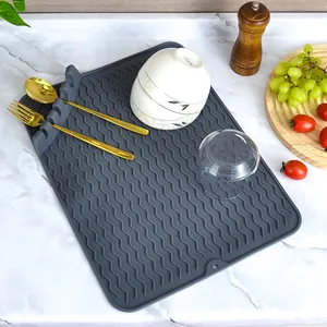 Grey silicone dish draining mat with wavy ridges and an integrated utensil rest