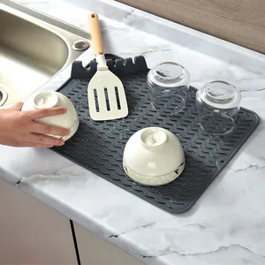 Grey silicone dish drying mat with integrated utensil rest on a marble countertop