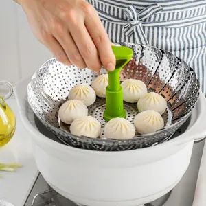 Panier vapeur pliable en acier inoxydable avec poignée verte et brioches dans un pot