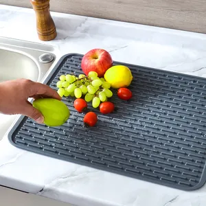 Dark grey silicone kitchen drying mat for dishes and fruits on marble countertop