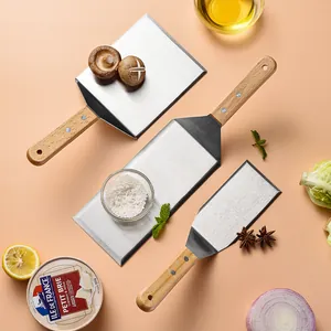 Stainless steel teppanyaki spatulas with wooden handles for cooking professional meals.