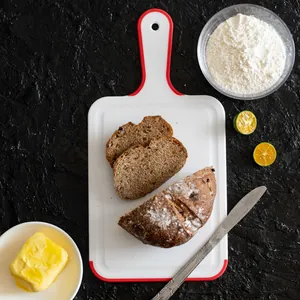 Premium white plastic cutting board with red non-slip handle and edges for kitchen food preparation