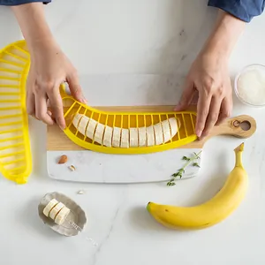 Yellow plastic banana slicer tool for creative kitchen fruit slicing on marble background