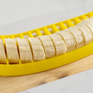 Plastic yellow banana slicer cutting uniform fruit pieces on a wooden board