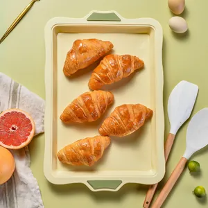 Pale yellow silicone baking tray with reinforced handles and fresh croissants.