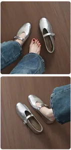 Detailed top view of chic silver round-toe Mary Jane flat ballet shoes on dark wood floor