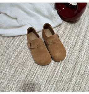 Detailed top view of tan suede slip-on clogs featuring adjustable buckle strap