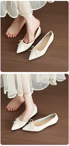 Dettaglio di eleganti ballerine a punta bianche con fiocco e gonna a pieghe bianca