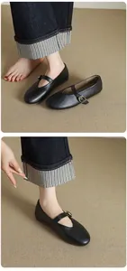Close-up of black leather Mary Jane flats worn with cuffed denim jeans
