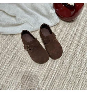 Top view of brown suede platform Birkenstock mules on a woven rug