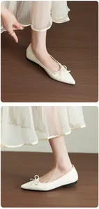 Dettaglio ravvicinato di ballerine a punta bianco crema con un elegante fiocco decorativo