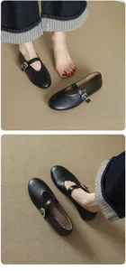 Elegant black leather round toe Mary Jane flats with single buckle strap detail.