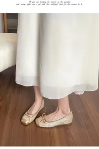 Dettaglio elegante di ballerine oro champagne con fiocco e punta quadrata su legno